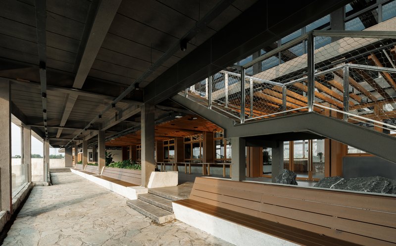 Interior circulation with exposed timber and steel beams beneath a mezzanine bridge