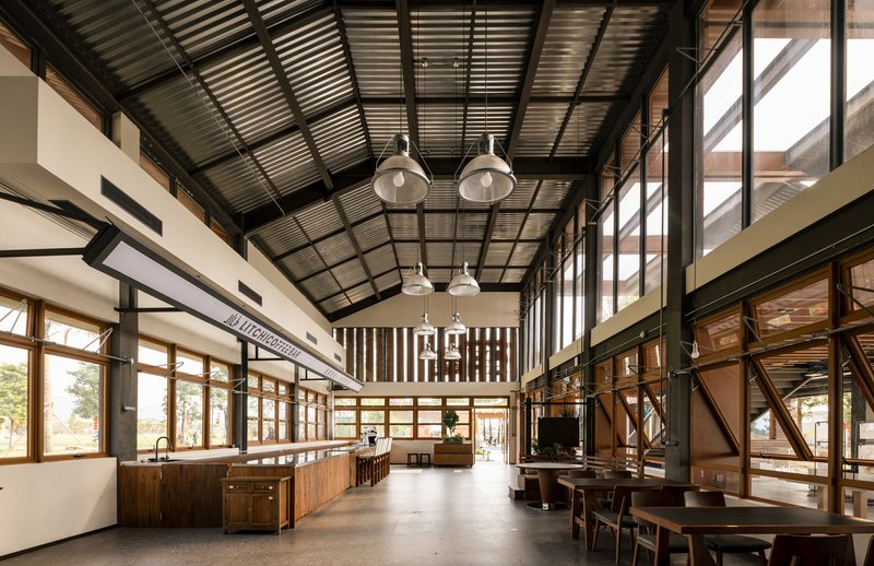 Open dining area with corrugated metal ceiling and timber screens filtering daylight
