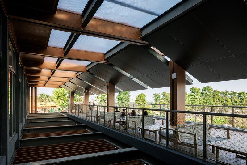 Open-air terrace with metal railings and timber bench seating under deep roof overhangs and skylights