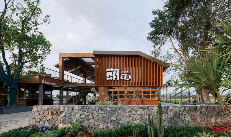 Entrance view of the timber-clad curved roof structure elevated on stone gabion walls with planted beds