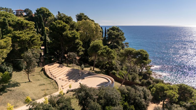 Aerial view of the amphitheatre and circular courtyard nestled in a wooded coastal site
