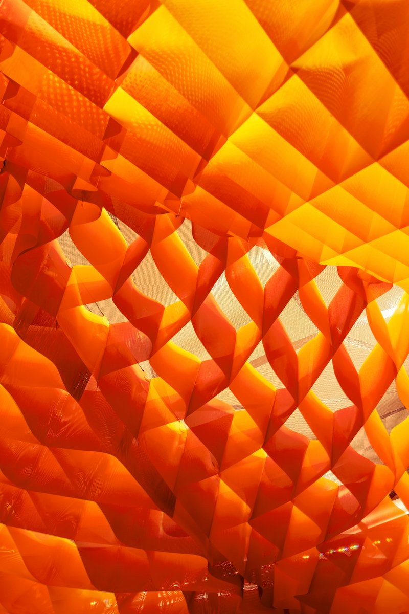 Close-up of the layered orange fabric panels with perforations creating a gradated diamond pattern