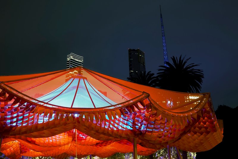 Night view of the illuminated orange canopy with palm trees and towers silhouetted behind