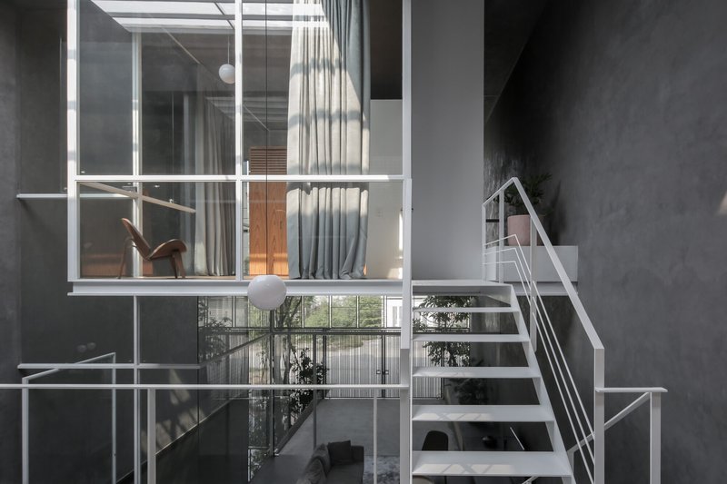 White metal staircase connecting multiple levels beneath a grid skylight with hanging globe lights