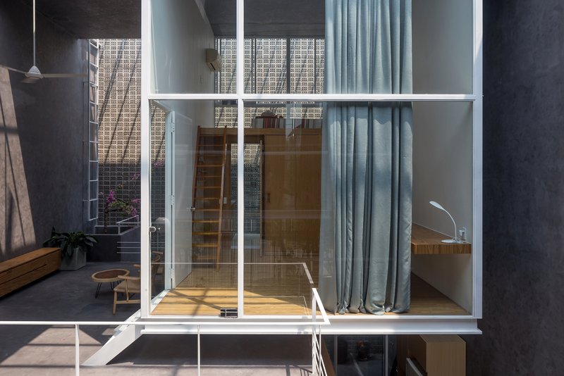 Glass-walled bedroom module with timber flooring suspended above the lower courtyard level