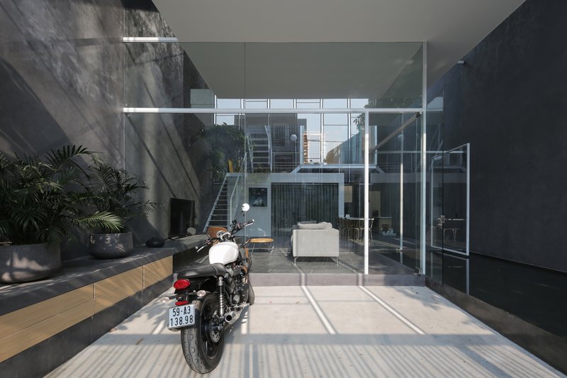 Ground-floor courtyard with motorcycle on striped concrete paving under clear skylight and white steel frame