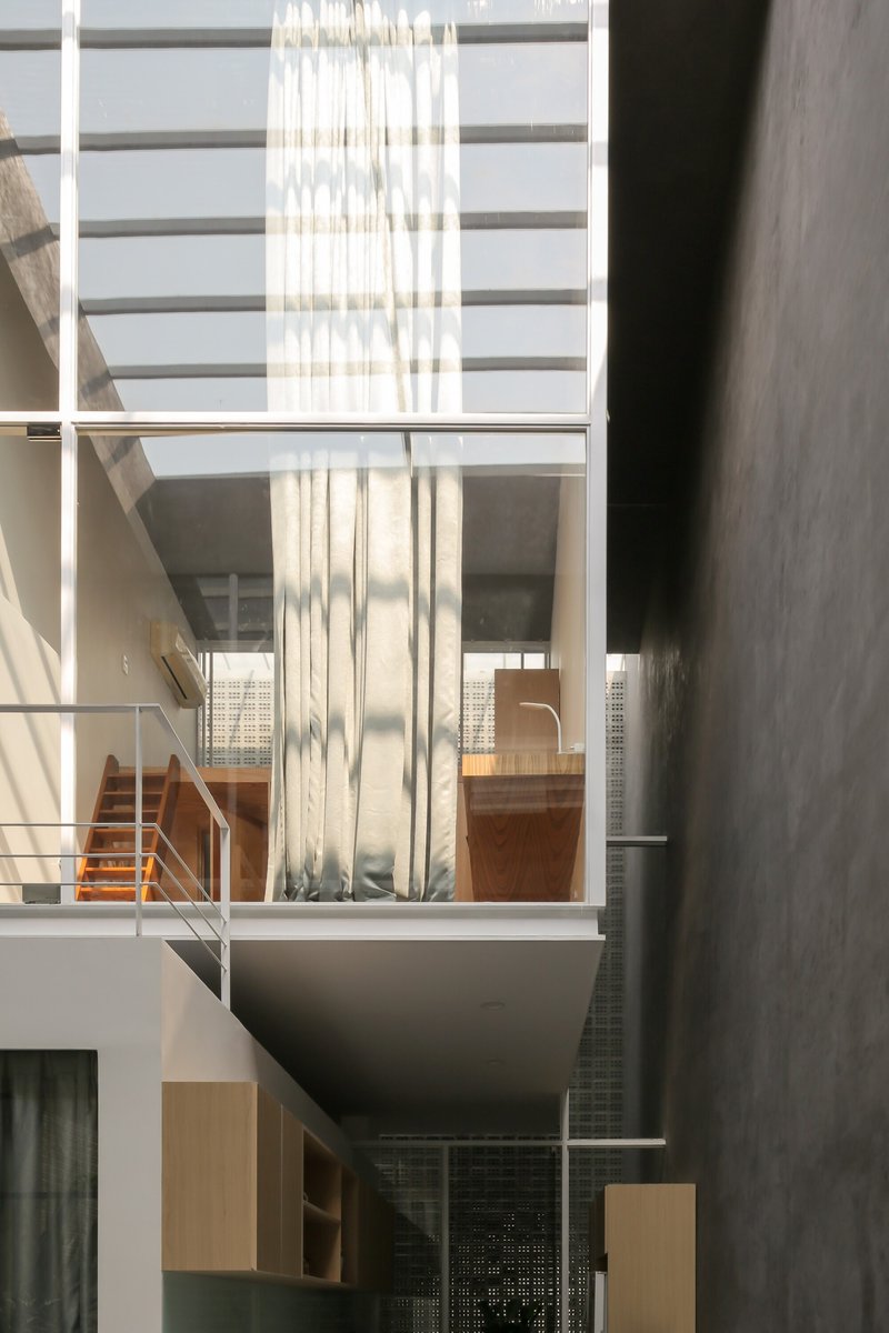 Vertical void with stacked mezzanine levels and translucent curtain filtering afternoon light from skylights above
