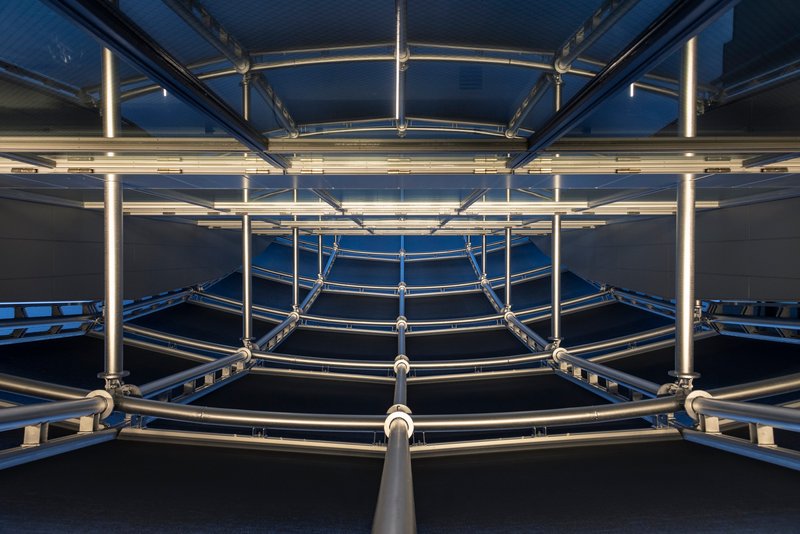 Upward view of circular steel structural rings with LED strips at dusk