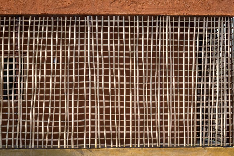 Close-up of the timber lattice screen grid with alternating shadows on earthen wall