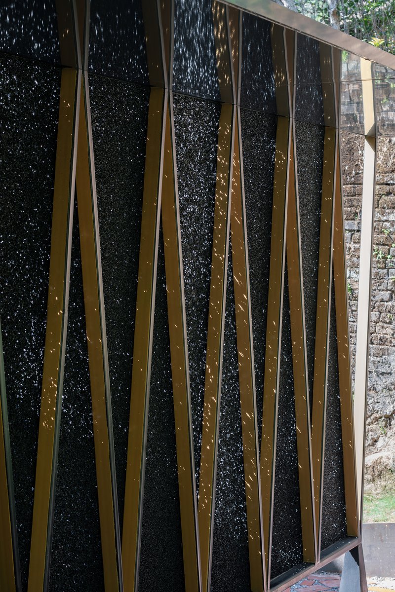 Close-up of the textured black panel system held by crossed bronze metal straps with visible rivets