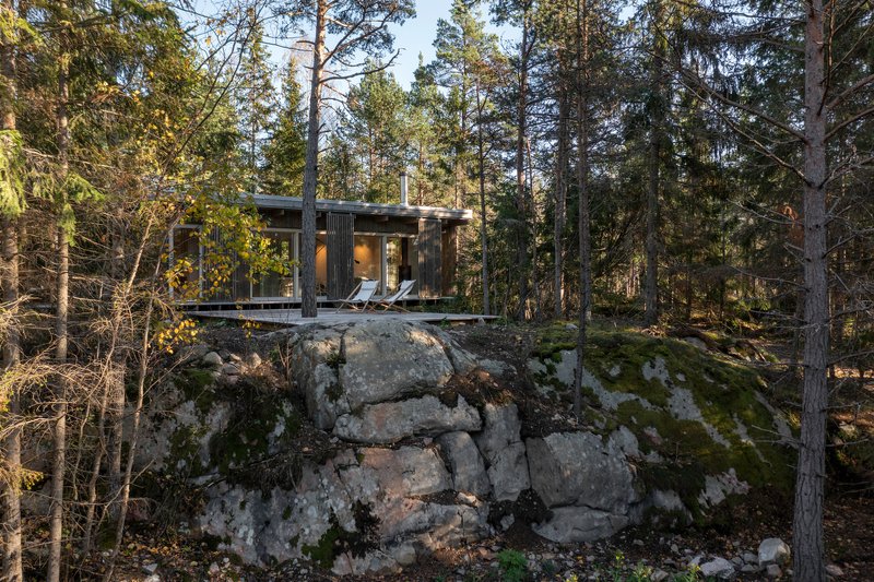 Elevated timber cabin perched on a glacial rock outcrop surrounded by pine forest