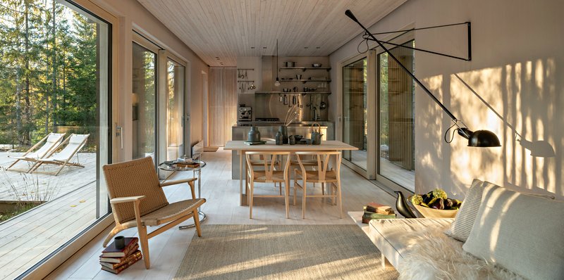 Open living and dining area with floor-to-ceiling glass and dappled afternoon light