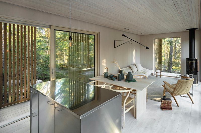 Open living space with stainless steel kitchen island and vertical timber screens filtering daylight