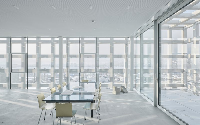 Glass-walled meeting room with sliding doors opening to a terrace framed by the perforated facade
