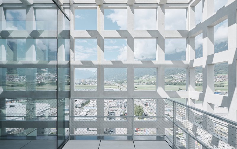 Geometric white sun screen casting patterned shadows across a glass-floored balcony with valley views