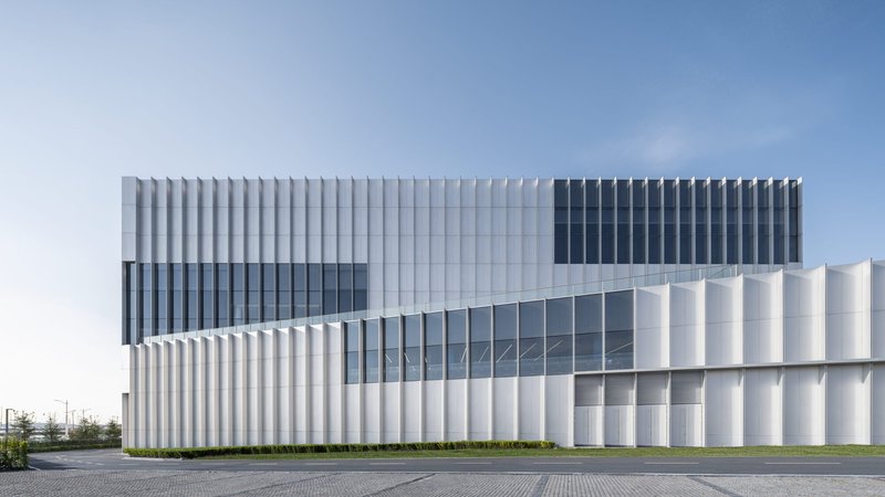 Side elevation showing the vertically ribbed metal cladding and horizontal glazed band under clear sky