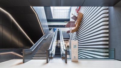 This architectural image showcases a modern museum interior featuring an escalator and stairs leadin