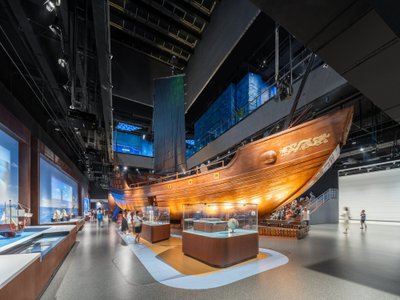 This architectural image showcases the interior of a museum featuring a large wooden ship as a centr
