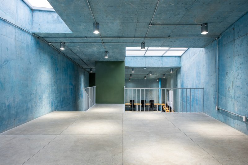 Upper level concrete floor with exposed ceiling, track lighting, and a rectangular skylight above the stair void