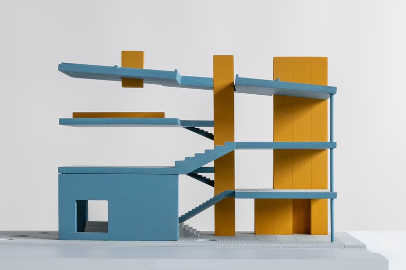 Sectional model revealing interconnected floor plates with diagonal staircases threading through yellow cores
