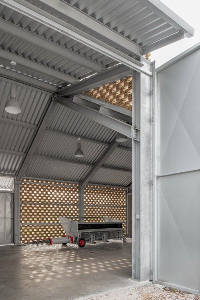 This architectural image showcases an industrial building with a corrugated metal roof and perforate