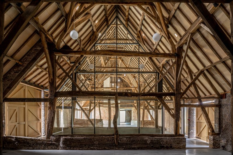 Exposed timber roof structure with diagonal bracing and pendant lights illuminating the central volume