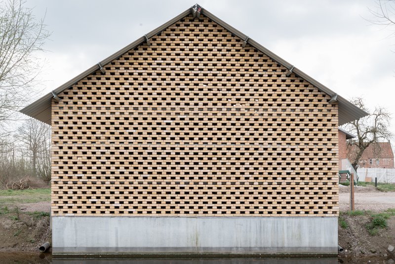Gable end with chequered brick pattern atop a concrete plinth under an overcast sky