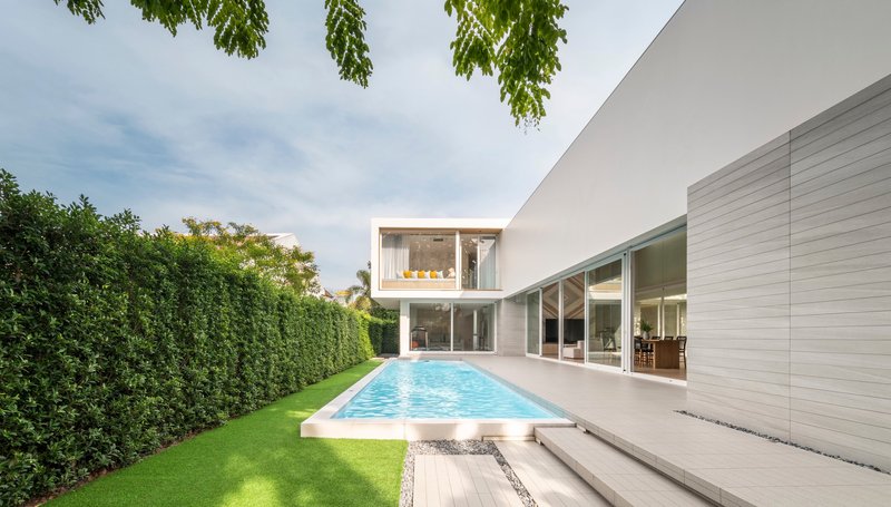 Rear courtyard with rectangular pool bordered by lawn and floor-to-ceiling glazing