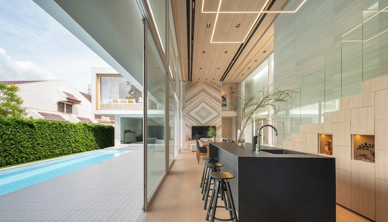 Kitchen island and sliding glass doors opening to pool terrace with trimmed hedge backdrop