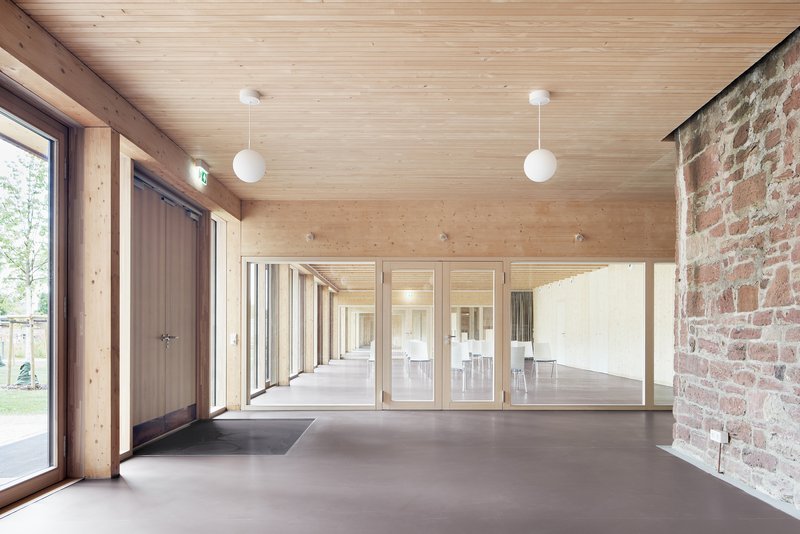 Timber-lined corridor with exposed brick wall and pendant lights leading to adjacent room