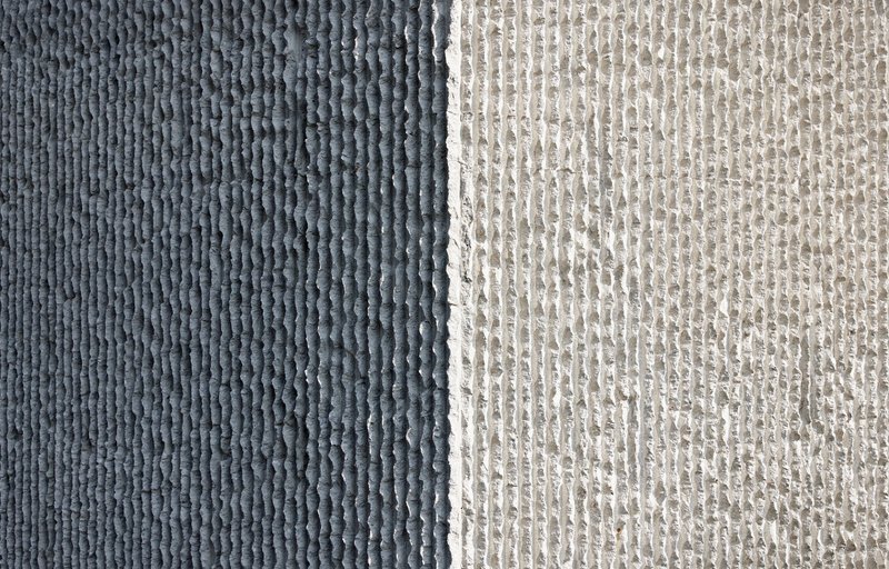 Close-up of two textured concrete panels showing dark grey and light grey ribbed formwork patterns