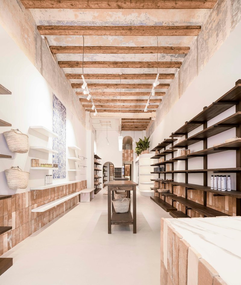 Retail interior with exposed timber ceiling beams and open shelving along whitewashed walls