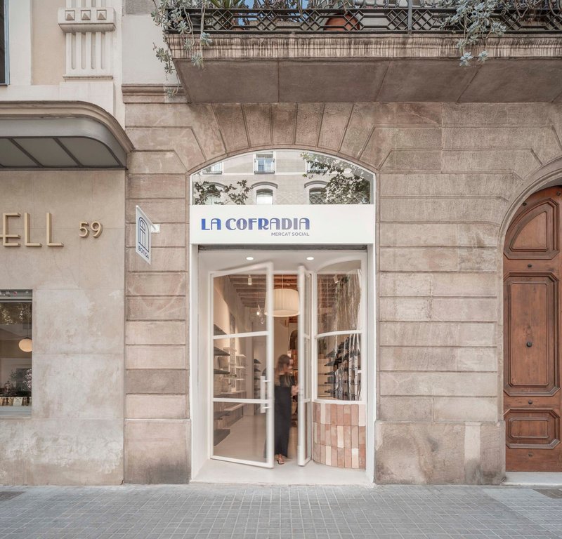 Street facade with arched stone entry and glazed doors beneath a planted rooftop terrace