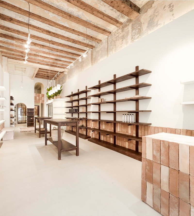 Open retail space with timber shelving unit and cork tile counters under exposed ceiling joists
