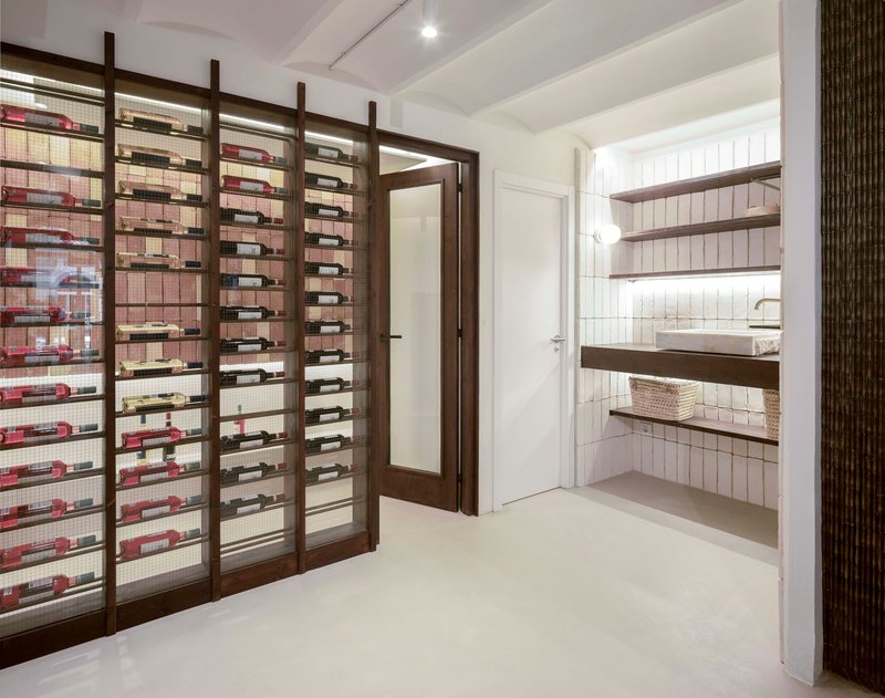 Timber and mesh wine rack framing a doorway with tiled bathroom visible beyond