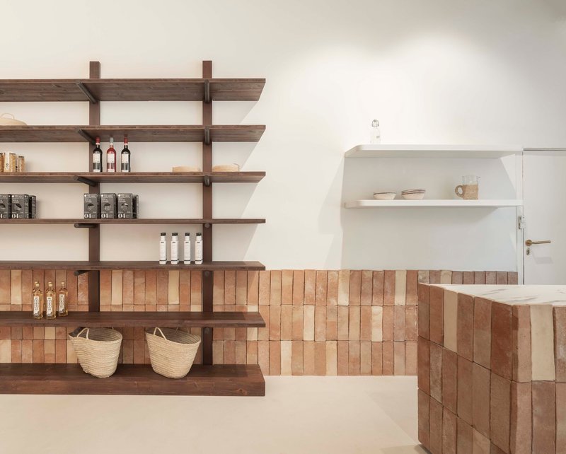 Walnut shelving unit and tiled counter with woven baskets against white walls in soft daylight