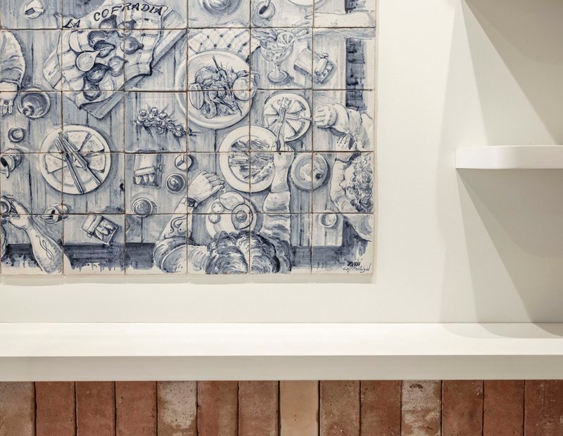 Blue and white ceramic tile mural depicting plates and tableware above stone tile counter