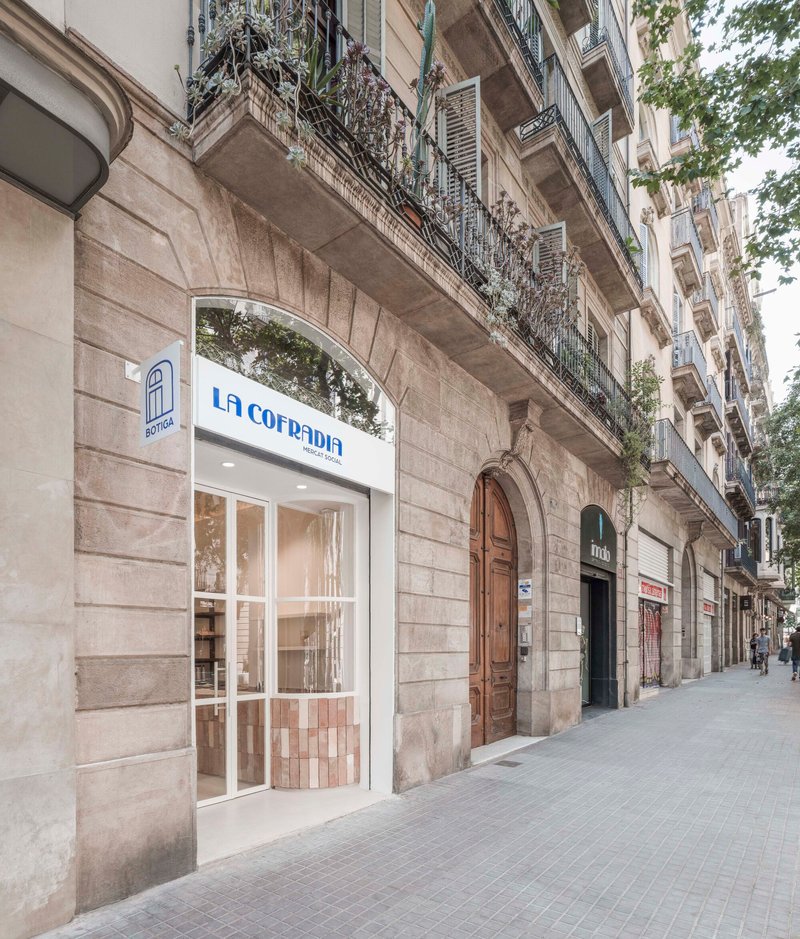 Street facade with arched storefront set into rusticated stone base of historic apartment building