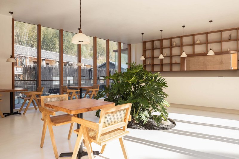Interior dining area with gridded timber shelving, pendant lights, and a planted bed beneath windows