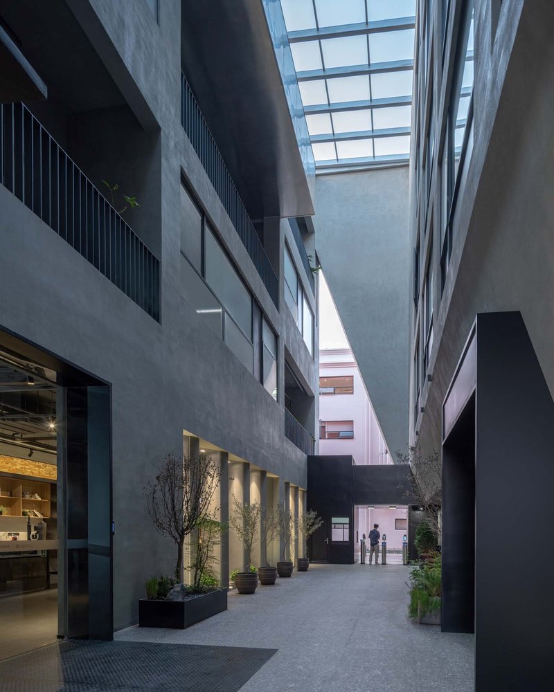 Interior courtyard with concrete walls, planted lighting along the base, and a glazed skylight overhead at dusk