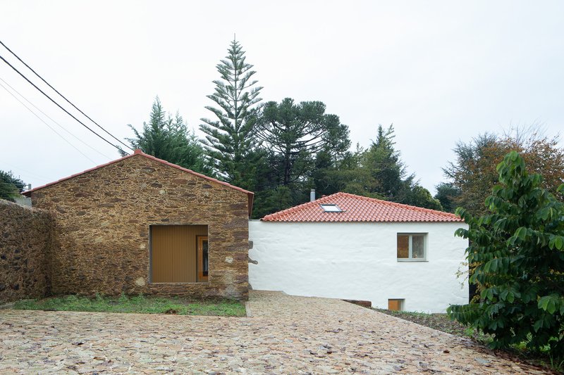 Courtyard view showing stone barn, white rendered house with tile roof, and cobblestone forecourt
