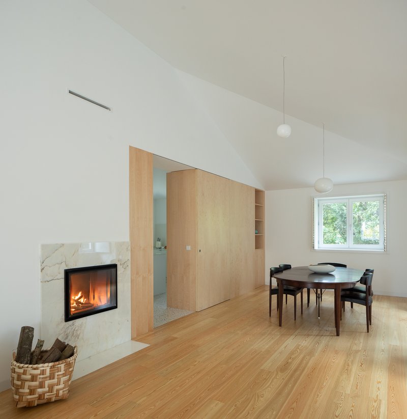 Living room with marble fireplace surround, sliding wood partition and pendant lights under a vaulted ceiling