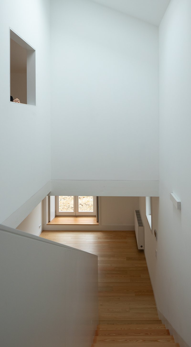 View down timber staircase into lower room with ribbon window framing autumn foliage outside