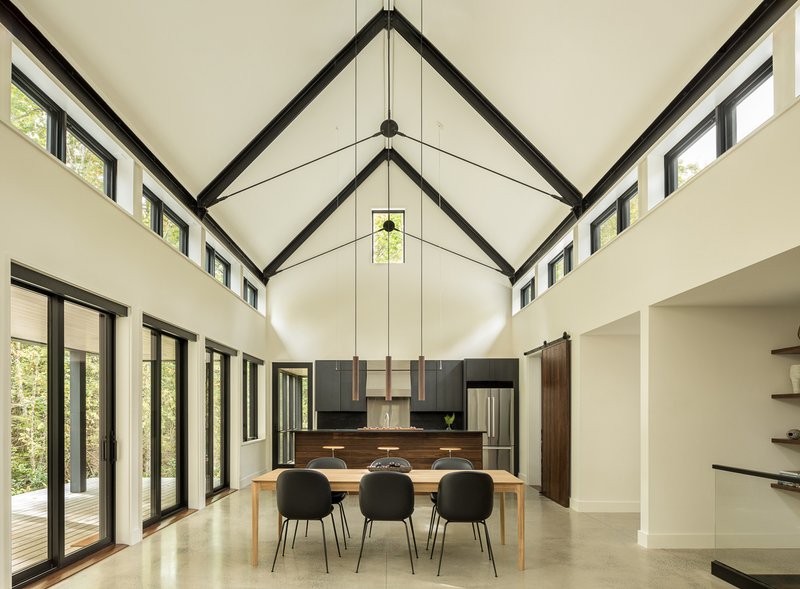 Vaulted ceiling with black steel trusses over dining area and polished concrete floor