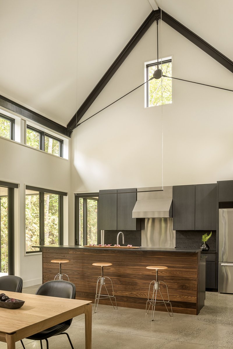 Kitchen island with walnut face and steel stools beneath exposed timber roof structure