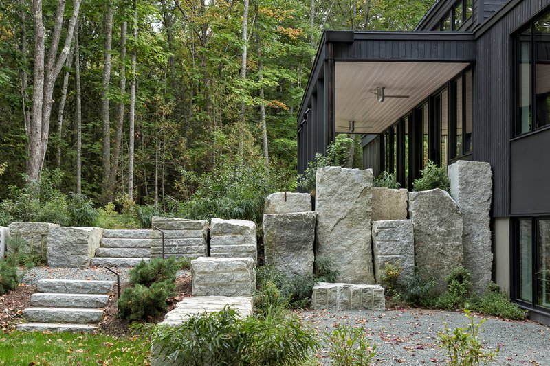 Stacked granite blocks forming a retaining wall with integrated stairs leading to the covered entry porch