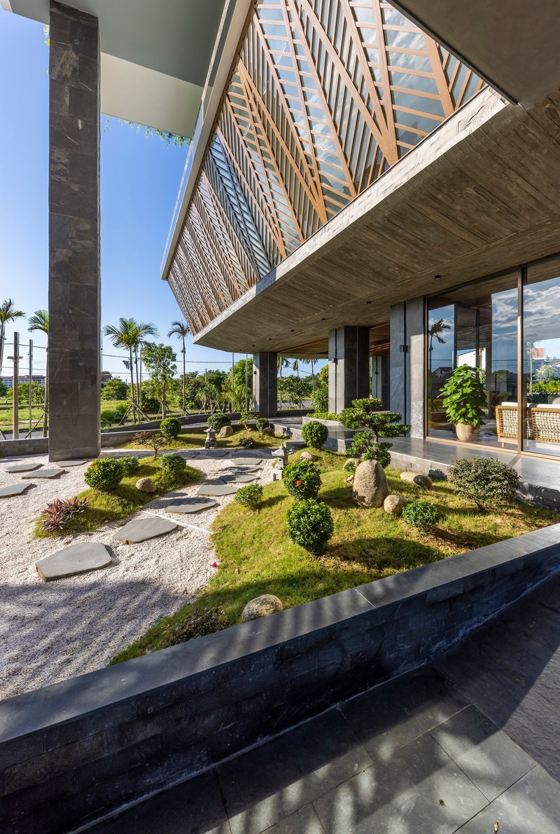 Zen garden under a cantilevered volume with timber lattice screens and stepping stones on gravel