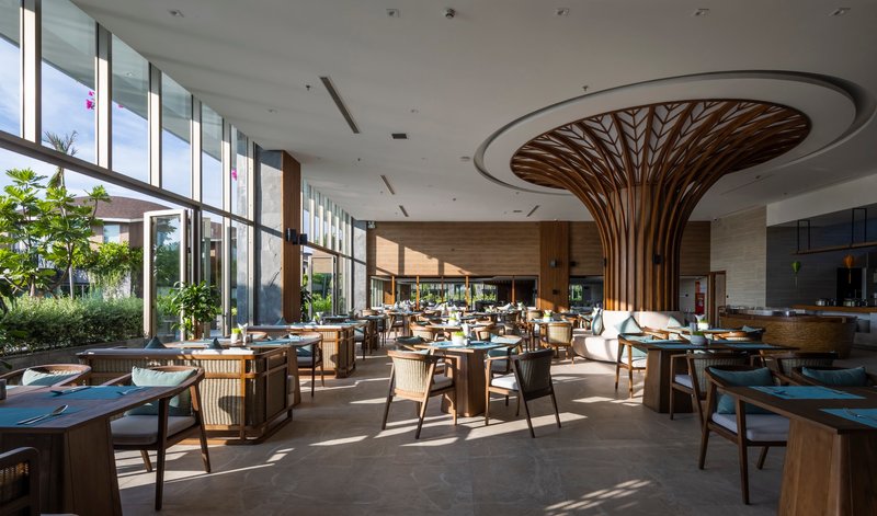 Dining area with a branching timber column supporting a circular ceiling recess under skylights