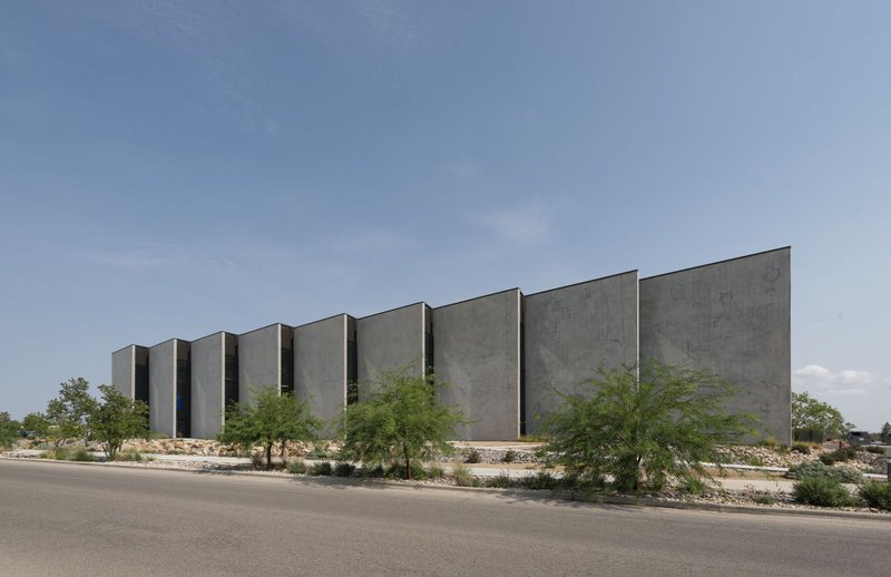 Street view of the sawtooth concrete facade with desert planting and gravel beds