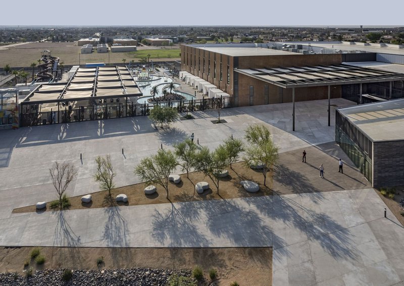 Aerial view of plaza with scattered boulders and young trees casting shadows on pavement